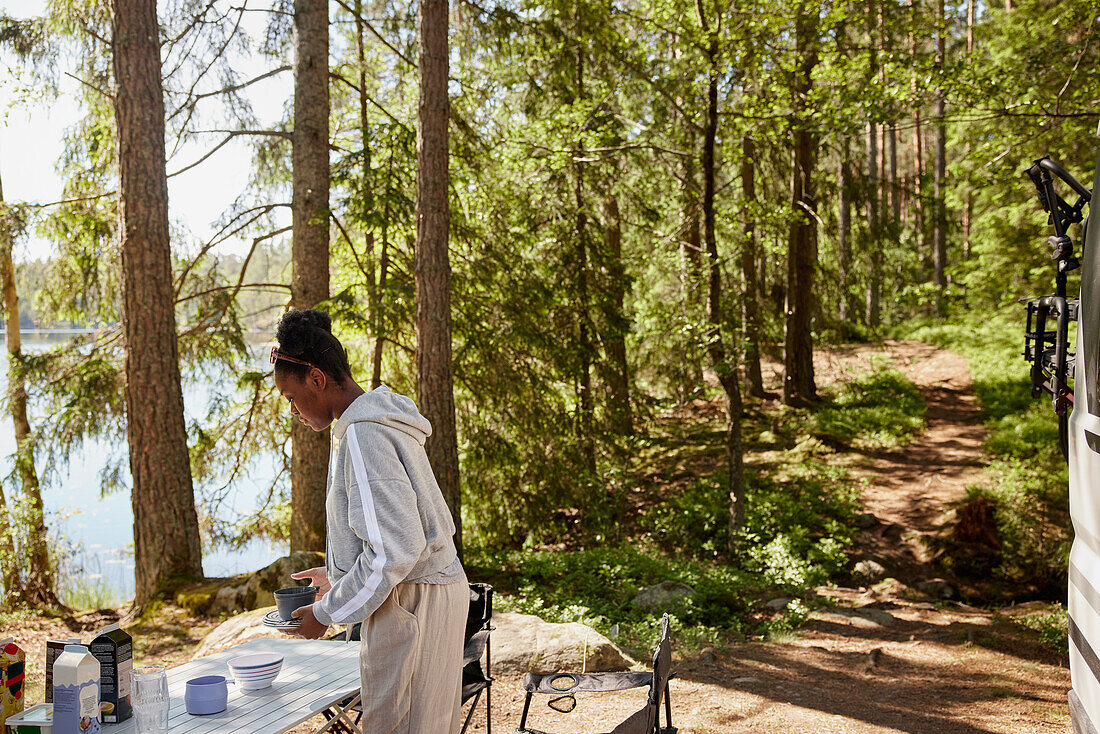 Woman collecting dishes from camping table