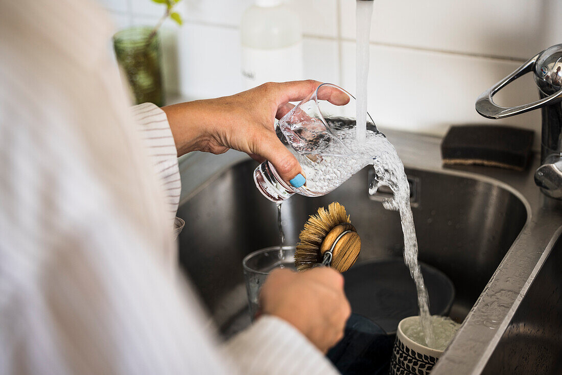 Woman washing dishes in kitchen sink