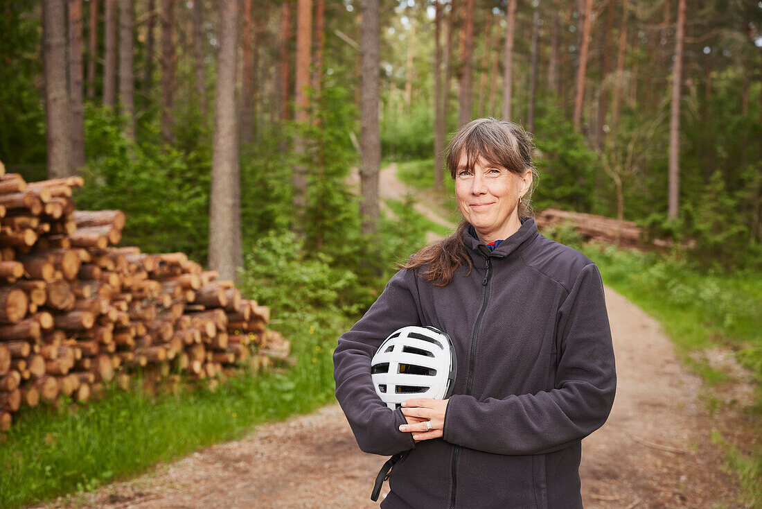 Portrait of woman holding bike helmet in forest