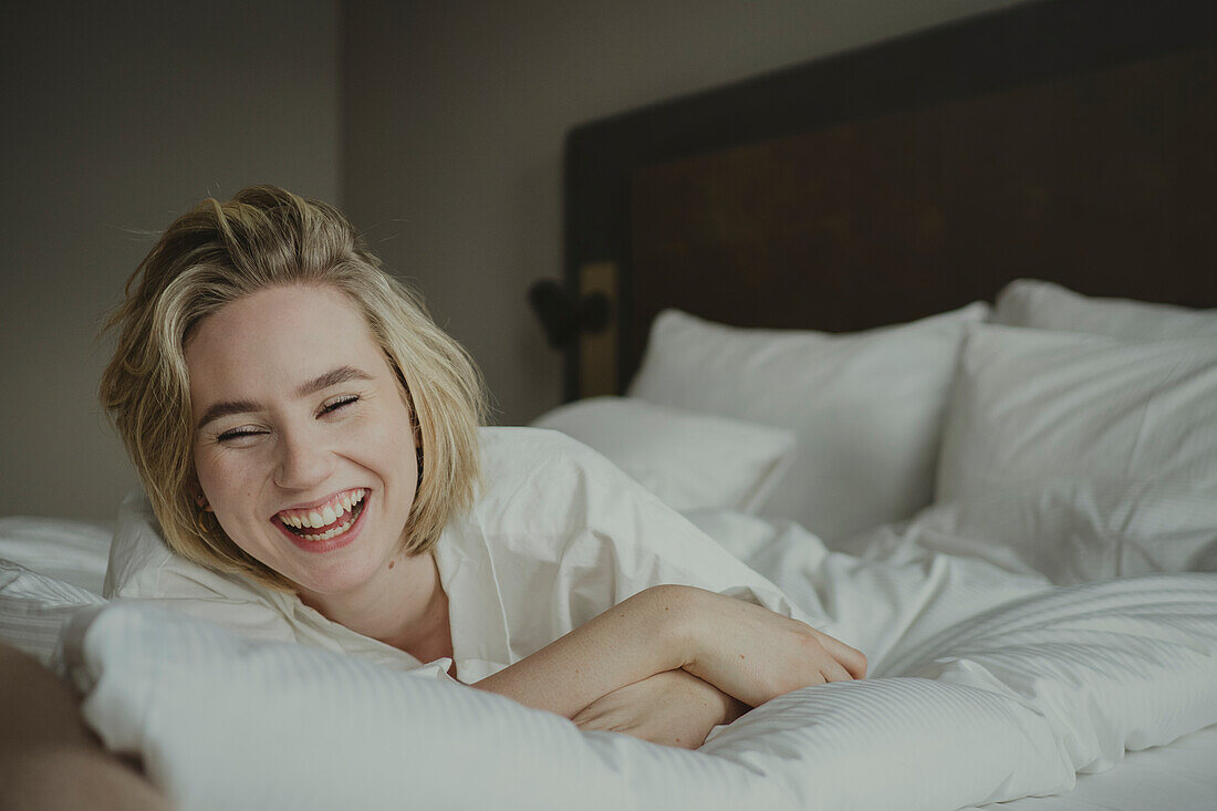 Blond woman laughing in bedroom