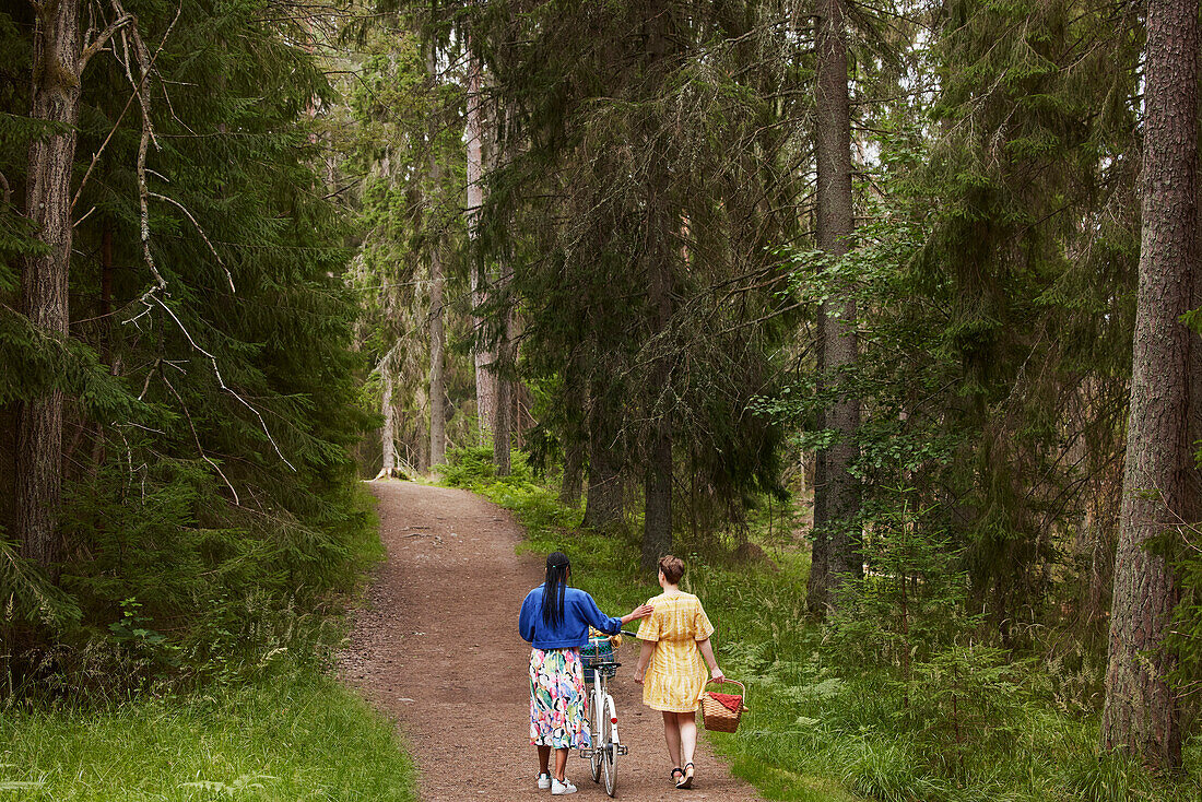 Weibliches Paar beim Spaziergang im Wald mit Fahrrad