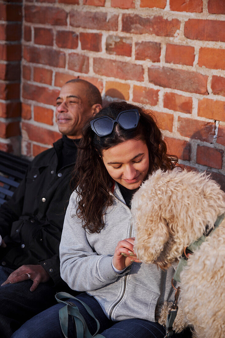 Pärchen mit Hund auf Bank sitzend