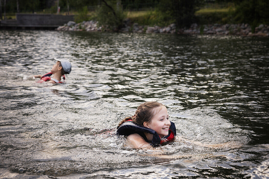 Siblings swimming in lake