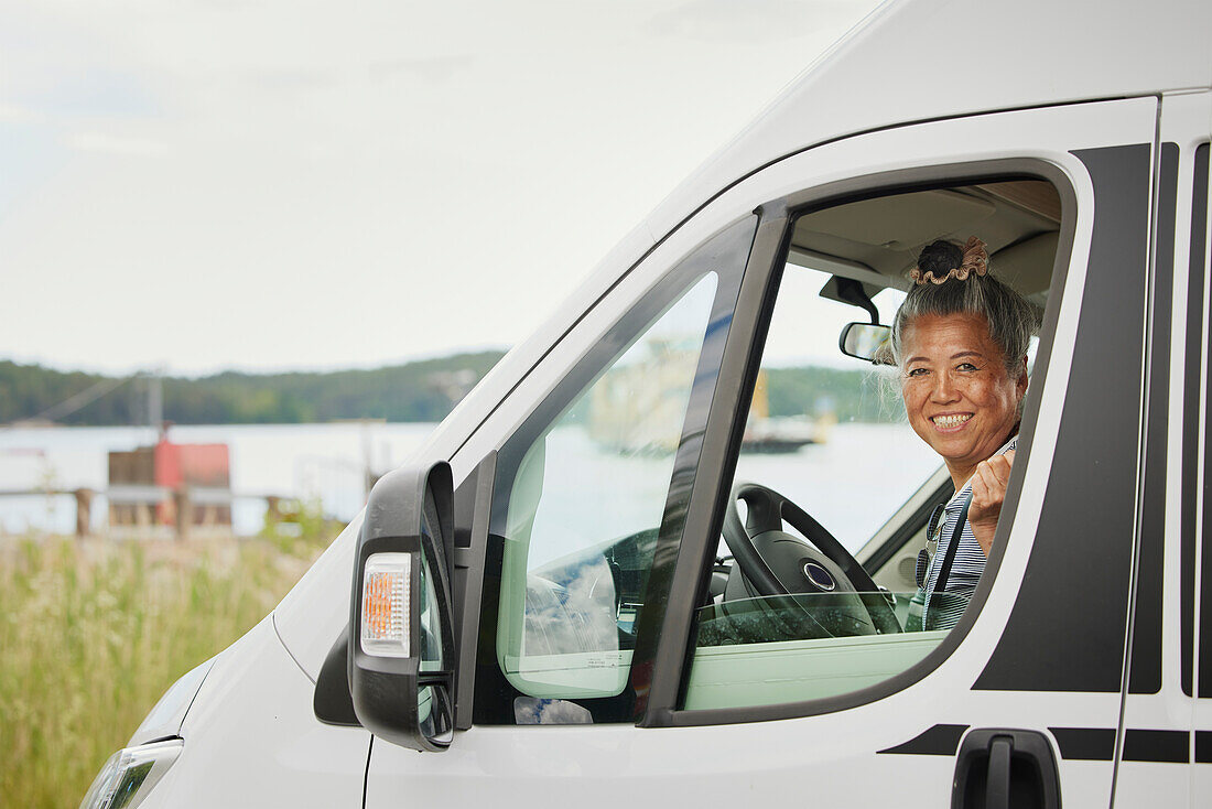 Porträt einer lächelnden älteren Frau, die in einem Lieferwagen sitzt