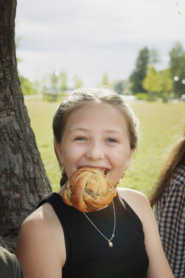 Lächelndes Mädchen isst Zimtschnecke