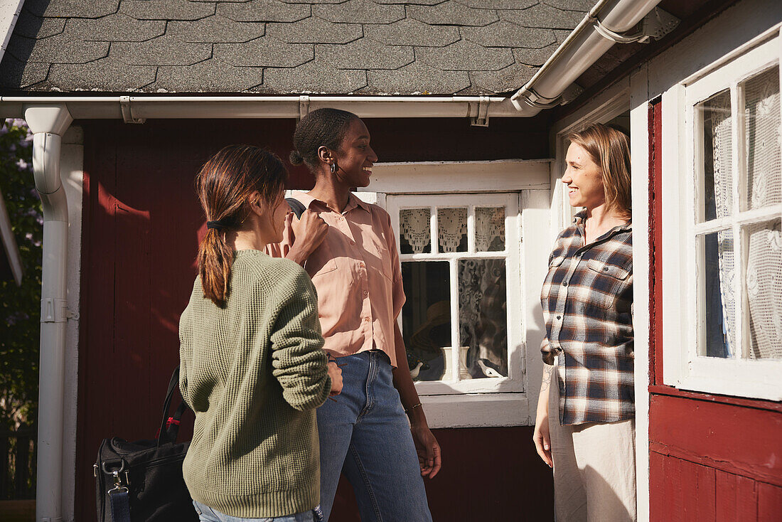 Smiling friends standing in front of wooden house