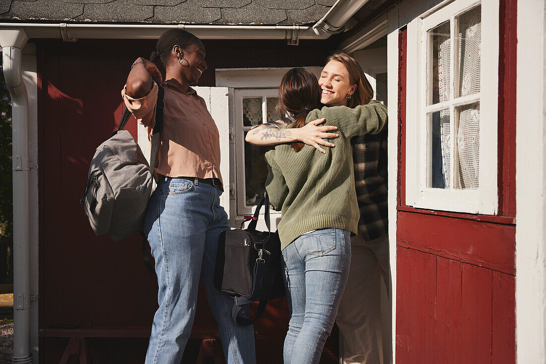 Smiling friends standing in front of wooden house