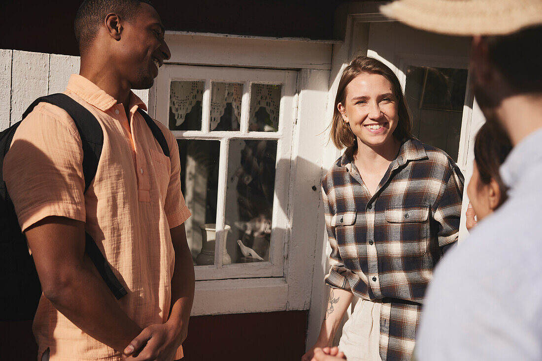 Smiling friends standing in front of wooden house