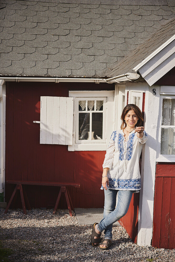 Smiling woman standing in front of wooden house