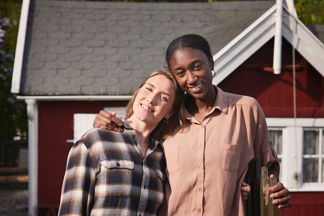 Smiling women standing in front of house