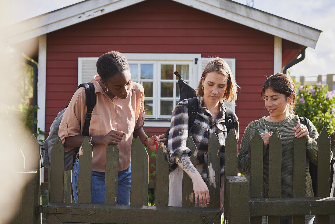 Female friends opening wooden gate