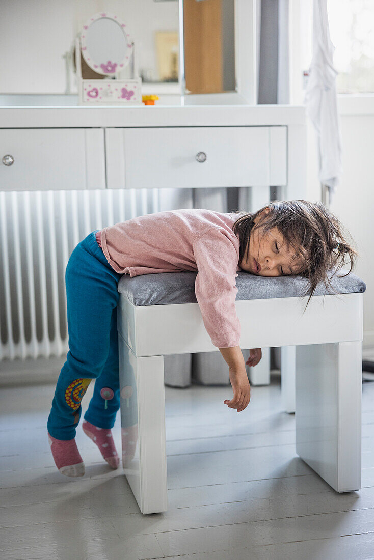 Müdes Mädchen schläft auf einem Hocker