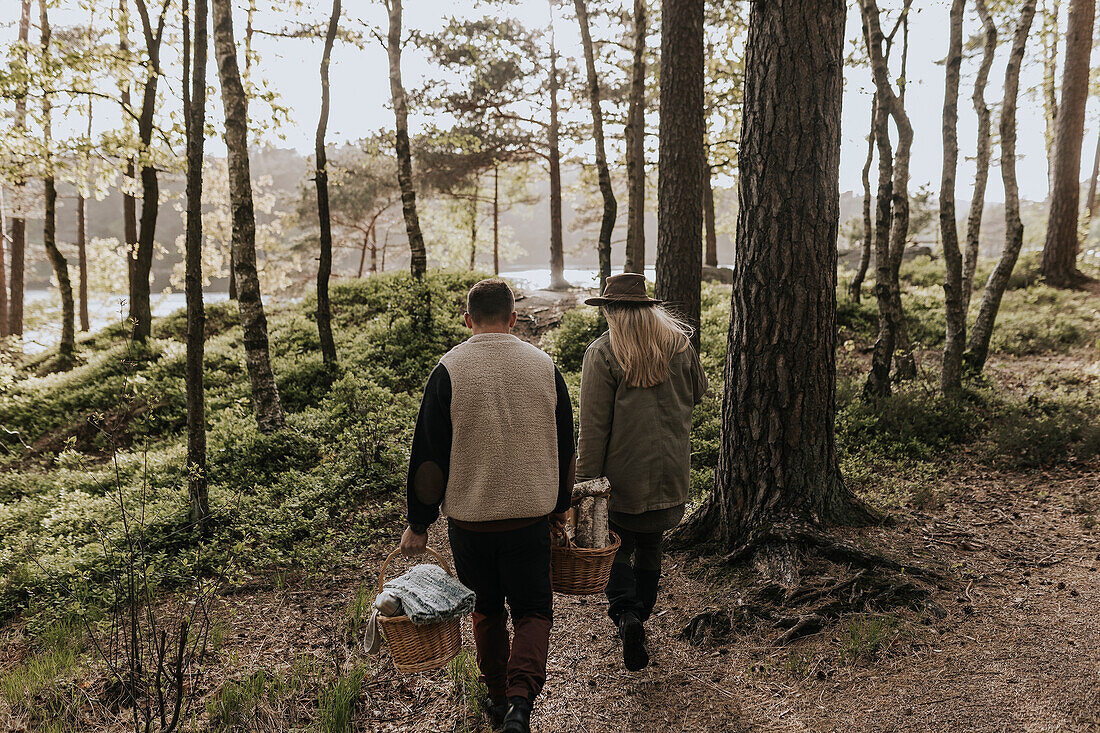 Rear view of couple walking through forest