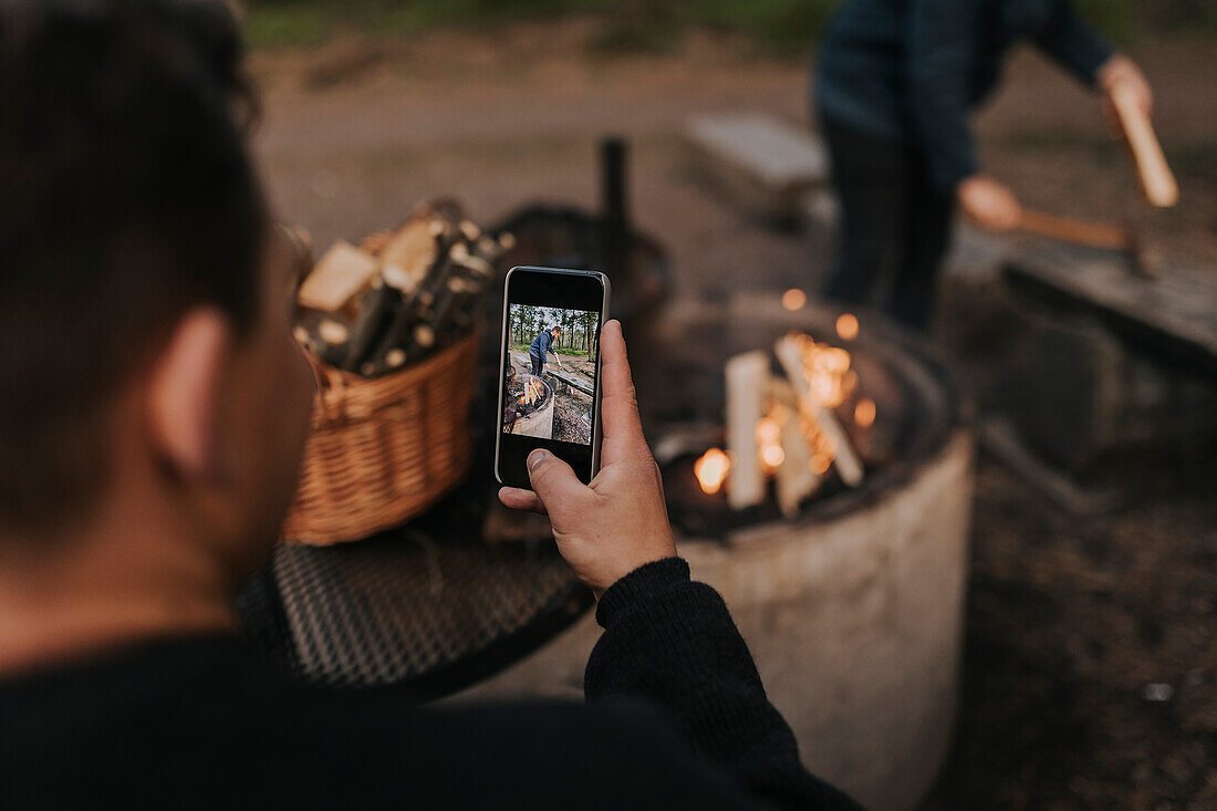 Man taking picture of friend chopping wood