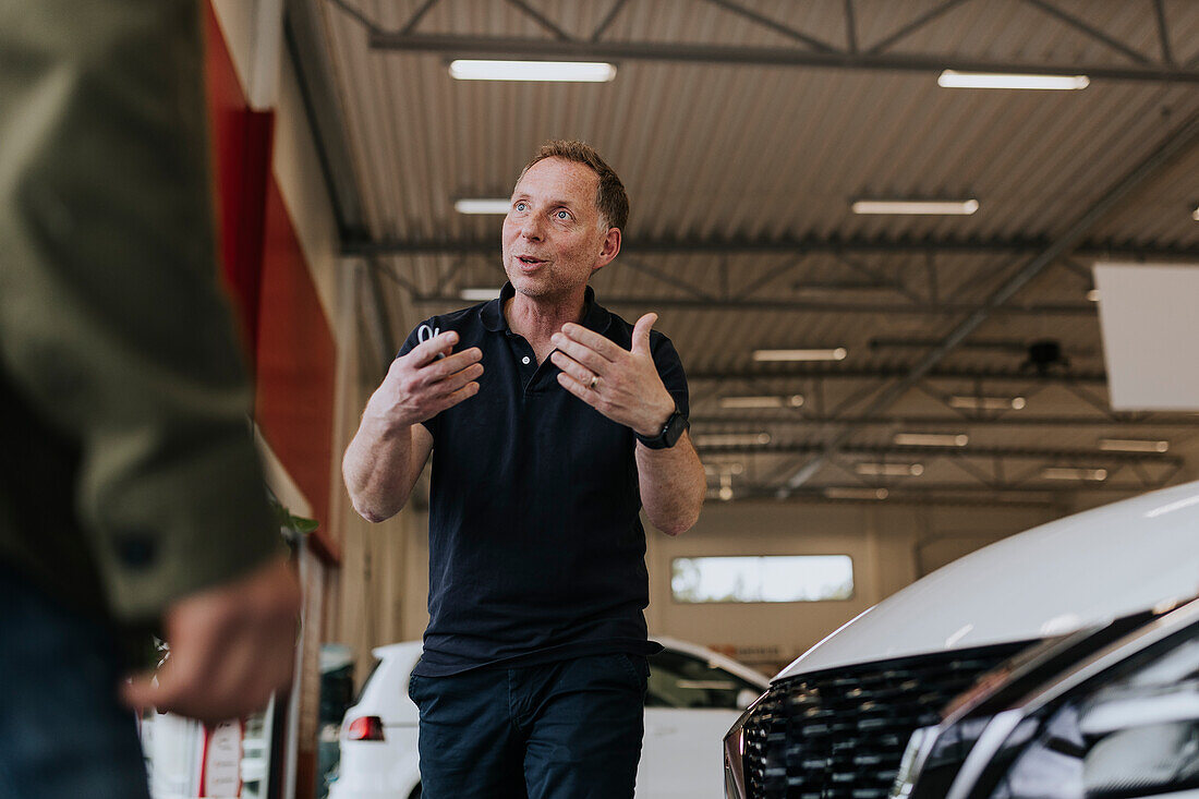 Salesman talking to customers in car dealership
