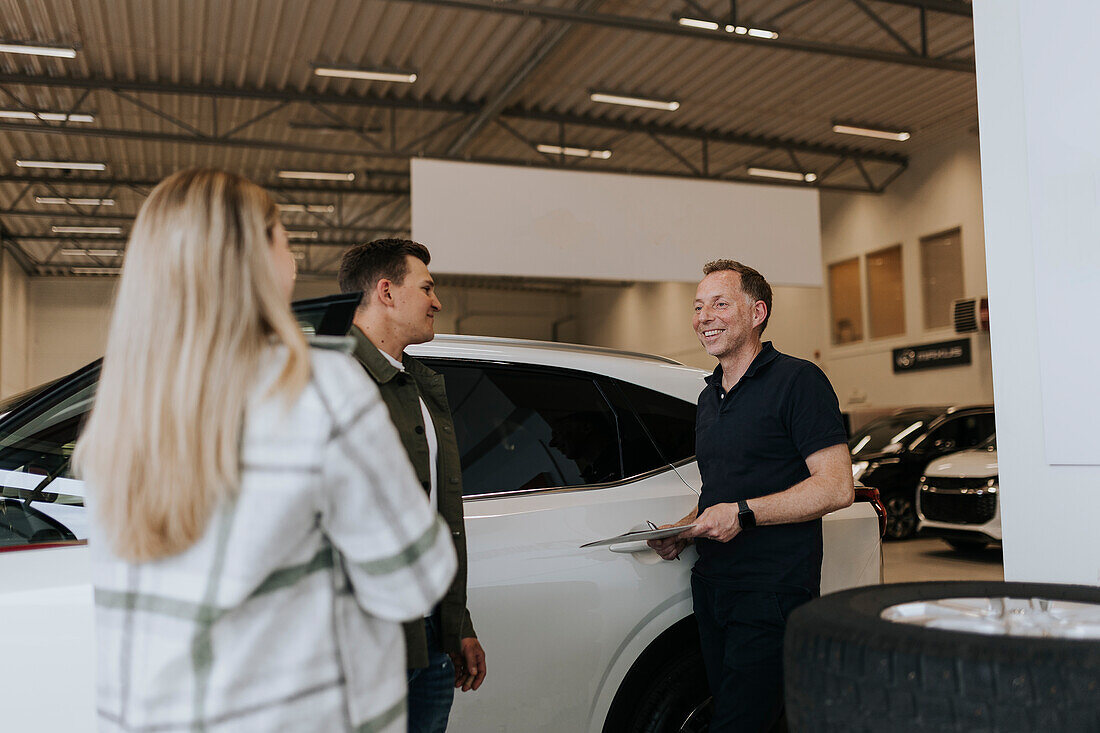 Salesman talking to customers in car dealership