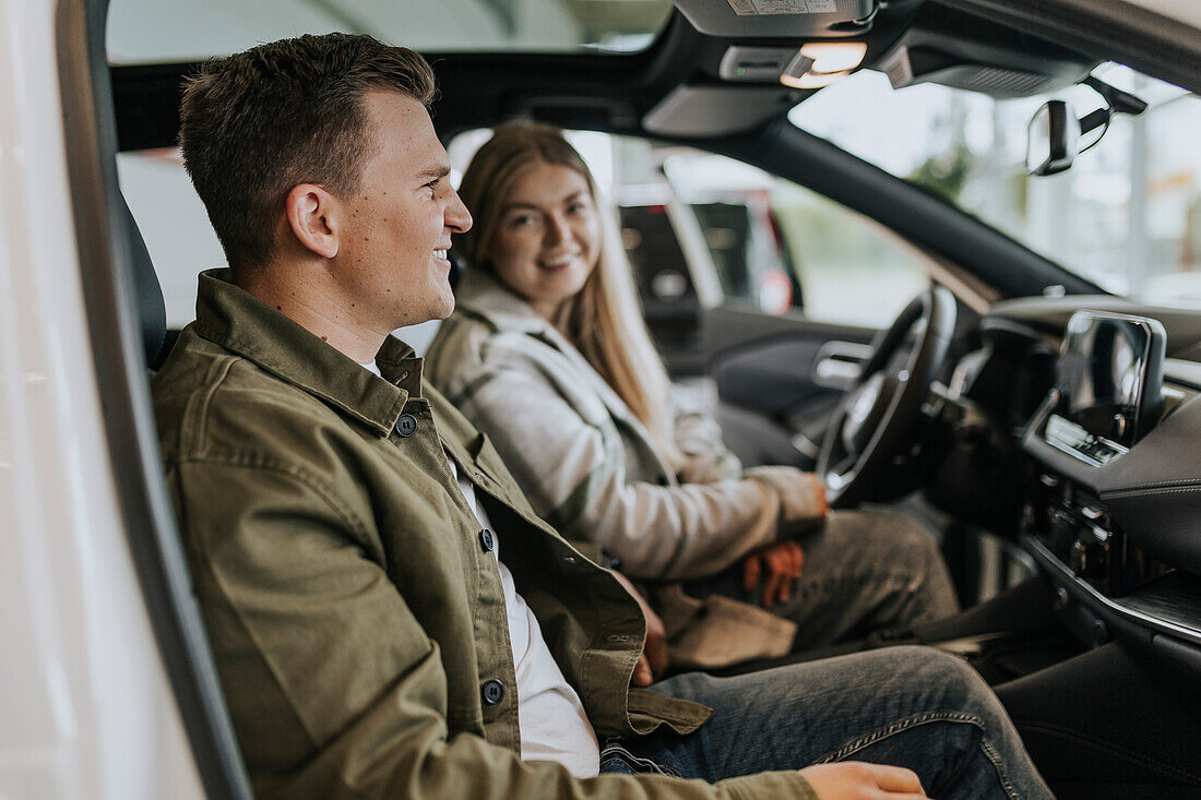 Junges Paar testet Auto im Autohaus