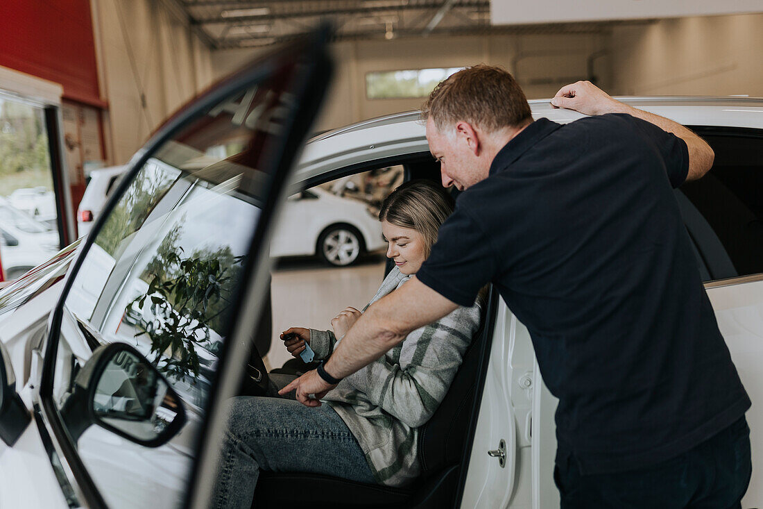 Salesman and female customer in car dealership