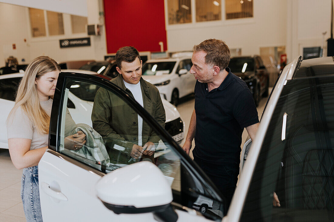 Verkäufer im Gespräch mit Kunden im Autohaus