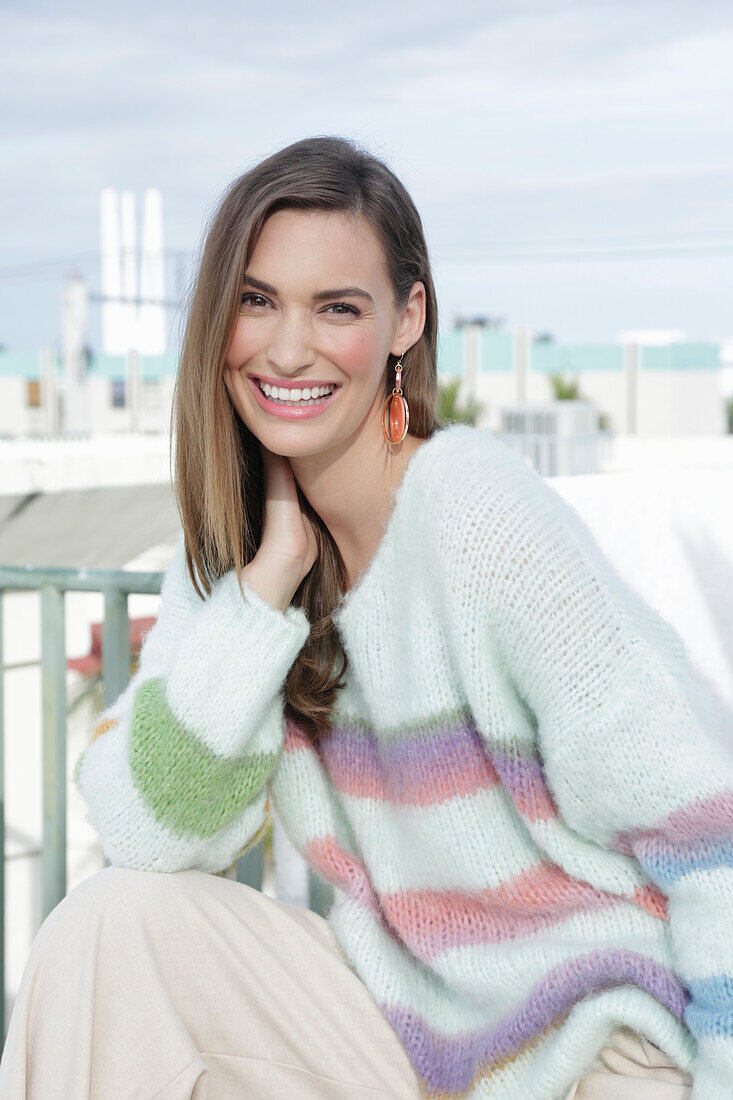 Young woman wearing a light knitted jumper with colorful stripes