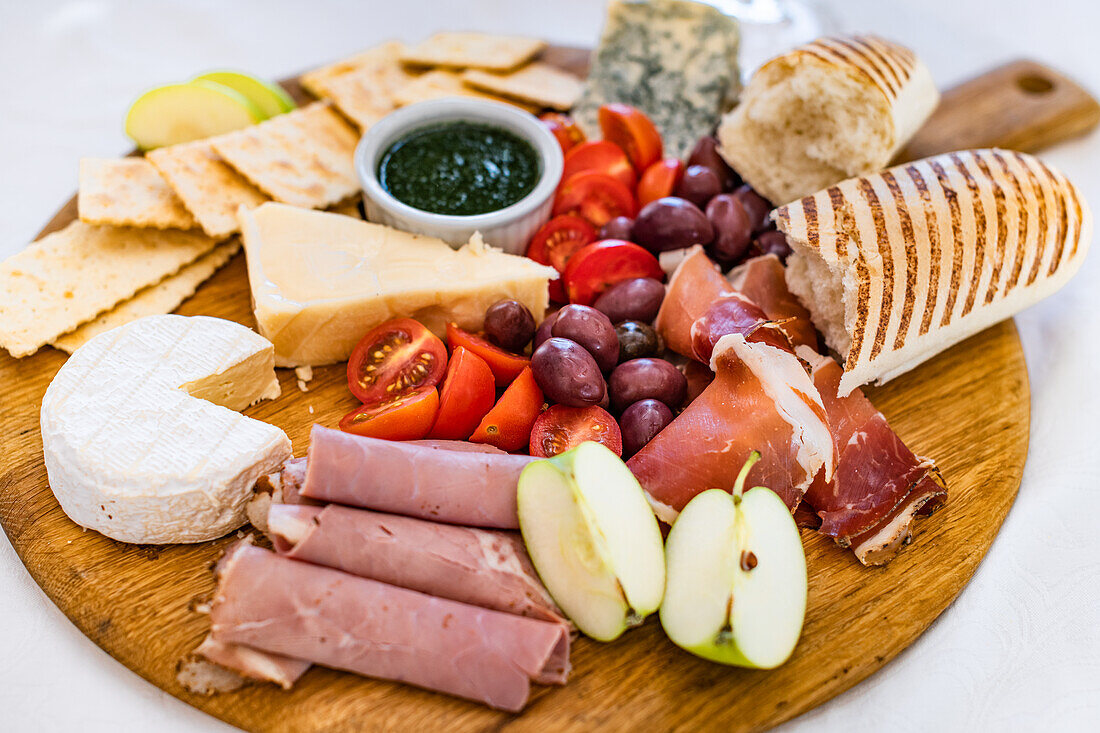 Käsebrett mit Brot, Schinken und Apfel, Oliven und Tomaten