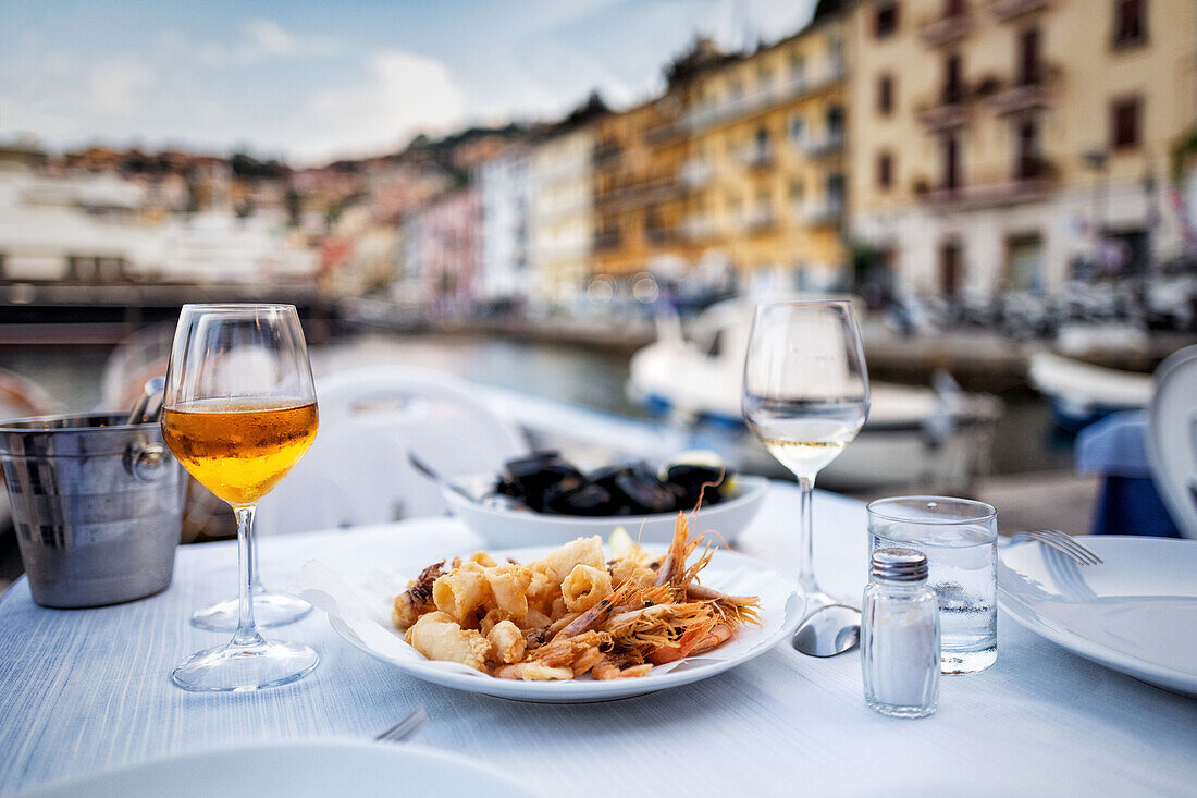 Fritto misto und Aperitif auf gedecktem Tisch mit Hafenblick (Italien)
