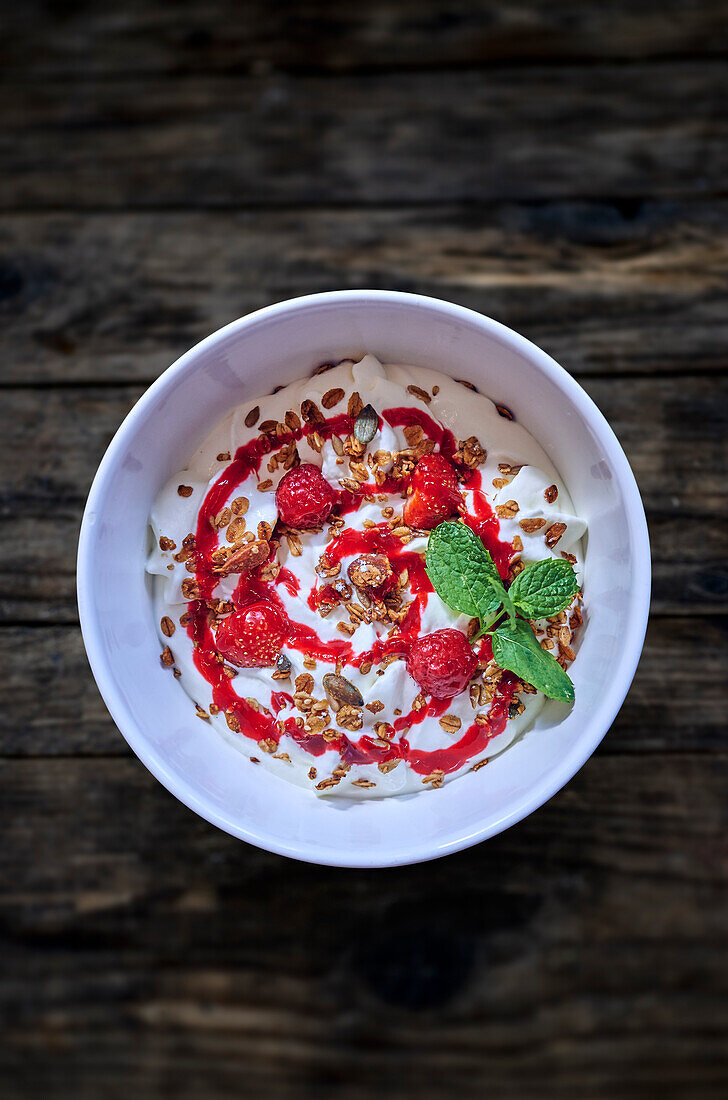 A bowl of yogurt with granola and berry sauce