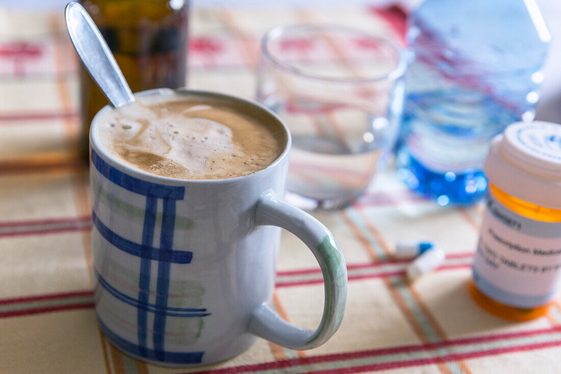 Medication next to a cup of coffee, conceptual image