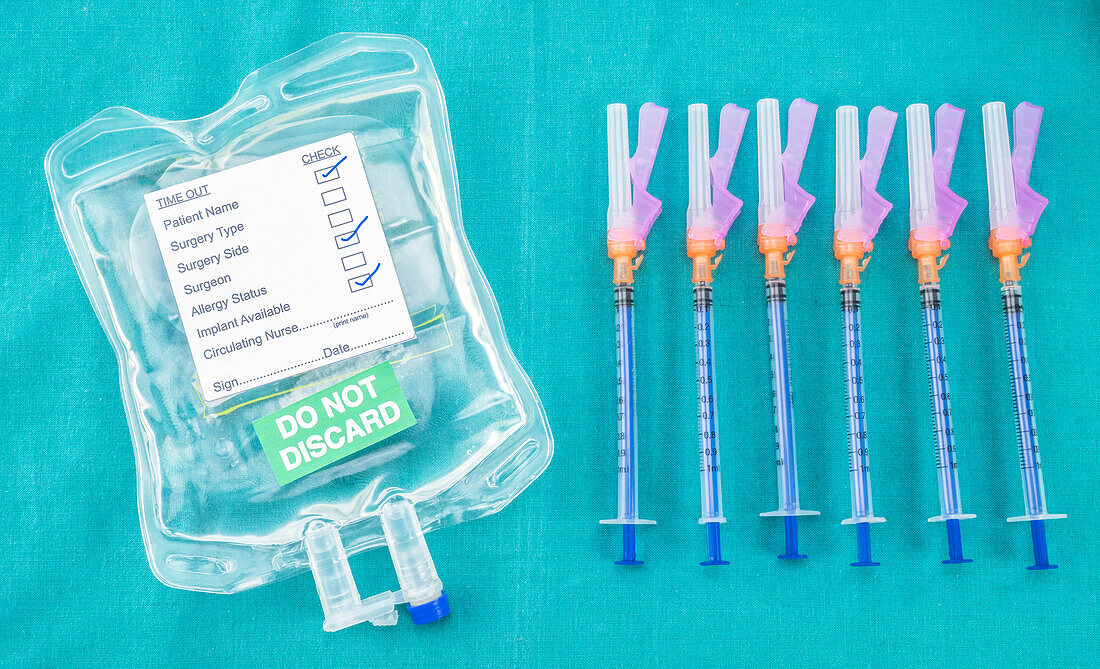 Syringes next to medical fluid bag, conceptual image