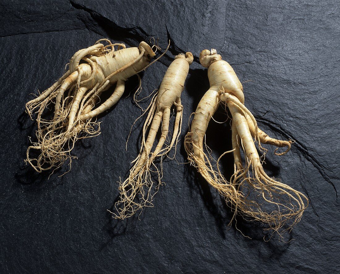 Three ginseng roots on a slate slab