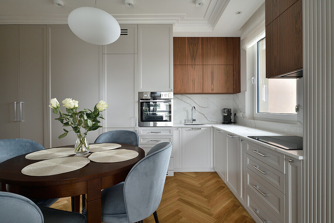 Fitted corner kitchen and round table with upholstered chairs