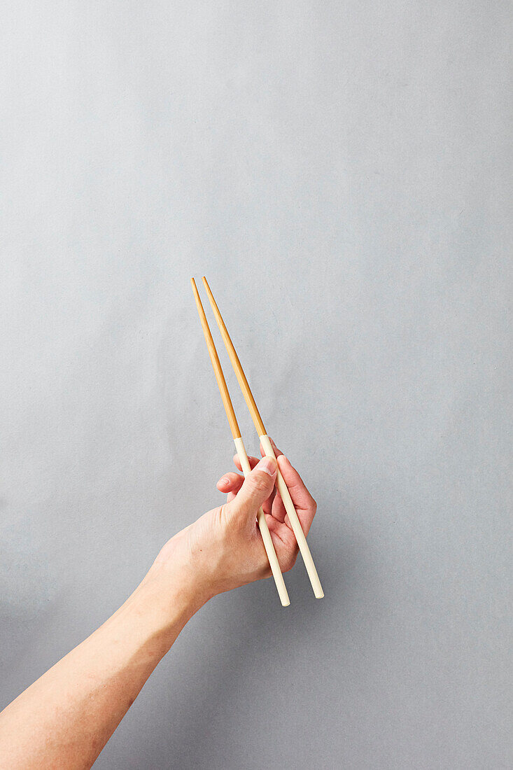 Hand holding chopsticks up