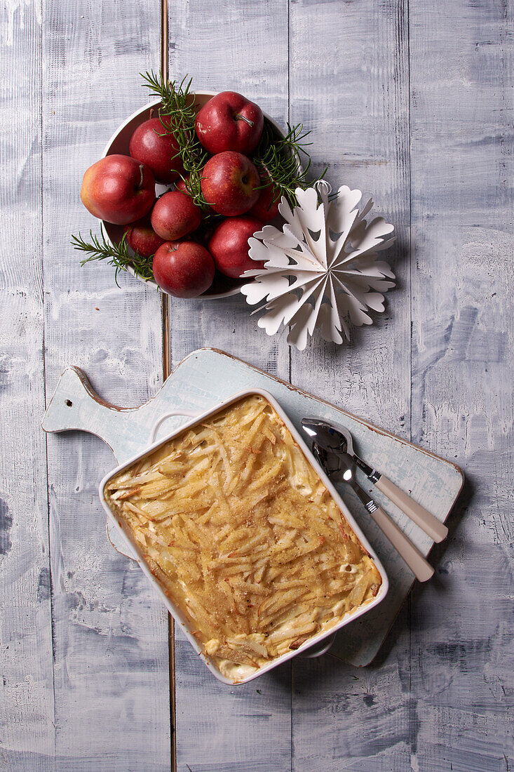 Potato and anchovy casserole with Christmas decoration and red apples