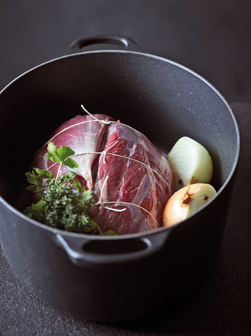 Rohes Rindfleisch mit Zwiebeln und Kräutern im Kochtopf