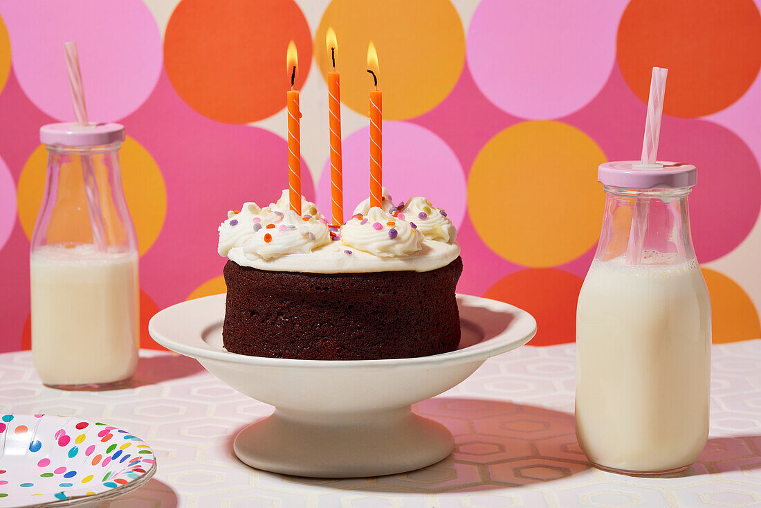 Chocolate birthday cake with vanilla icing and three orange candles