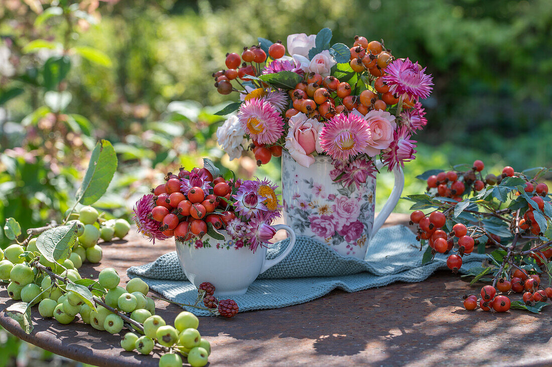 Autumn bouquet with rose hips, strawflowers and roses in nostalgic tableware