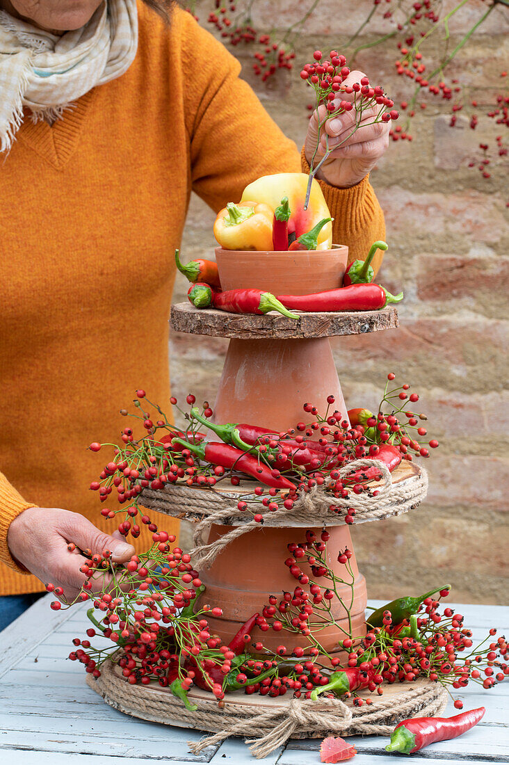 Homemade cake stand made of clay pots and wooden discs with rose hips