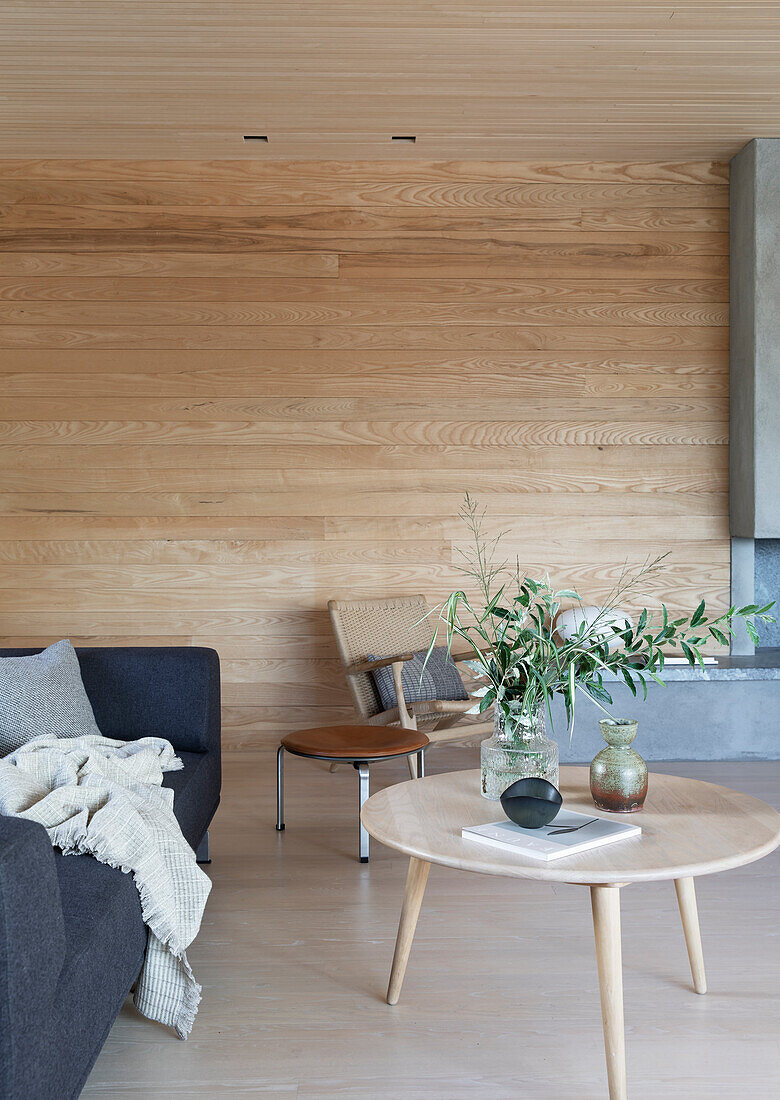 Sofa with coffee table in light room with wood paneled walls