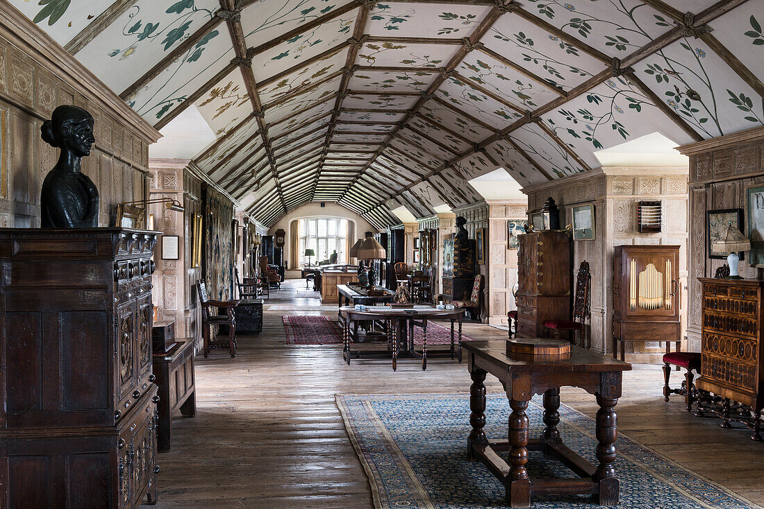 Oliver Messel’s 20th century twining foliage of English trees in long gallery with antique furniture and busts