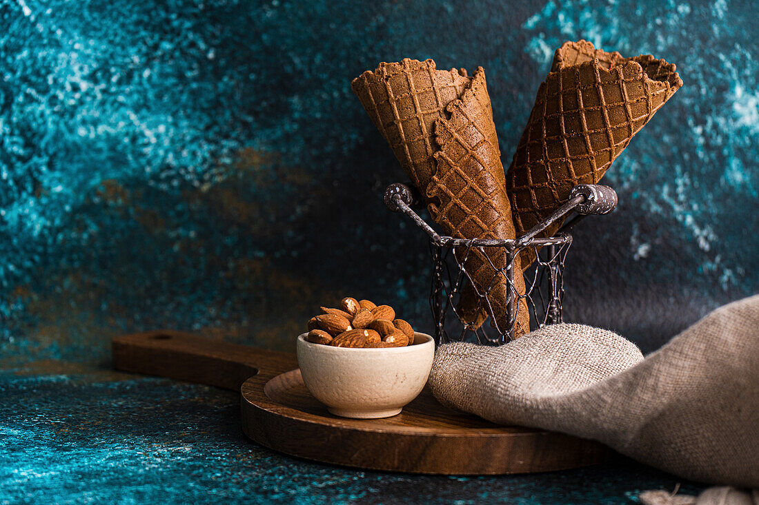 Empty ice cream cones in a basket and almonds in a bowl