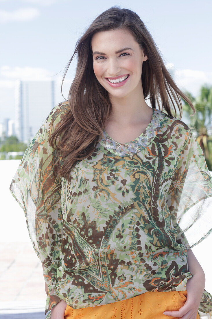 A young woman wearing a colorful, airy summer blouse