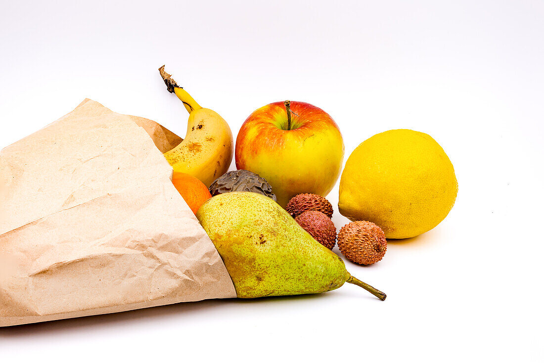 Eine nachhaltige Papiertüte mit verschiedenem Obst freigestellt als Studioaufnahme vor weißem Hintergrund