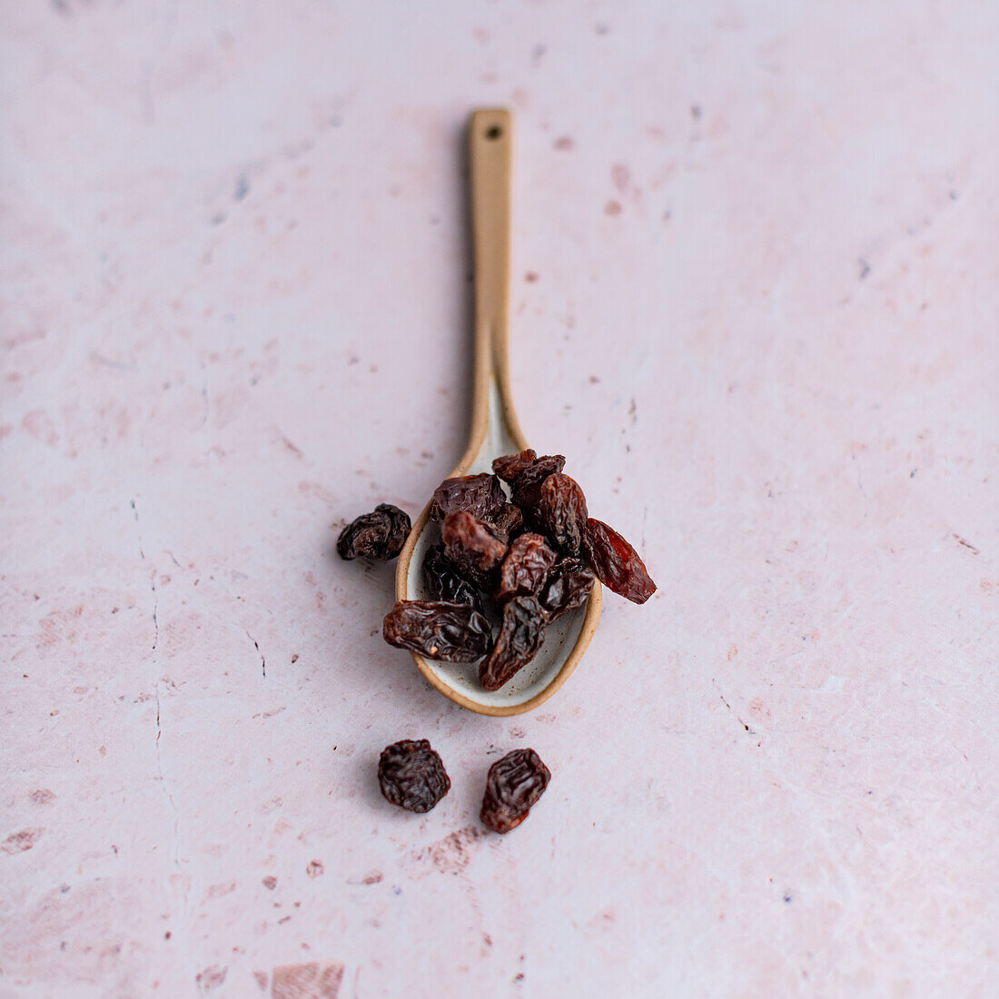 Spoon with raisins on a purple background