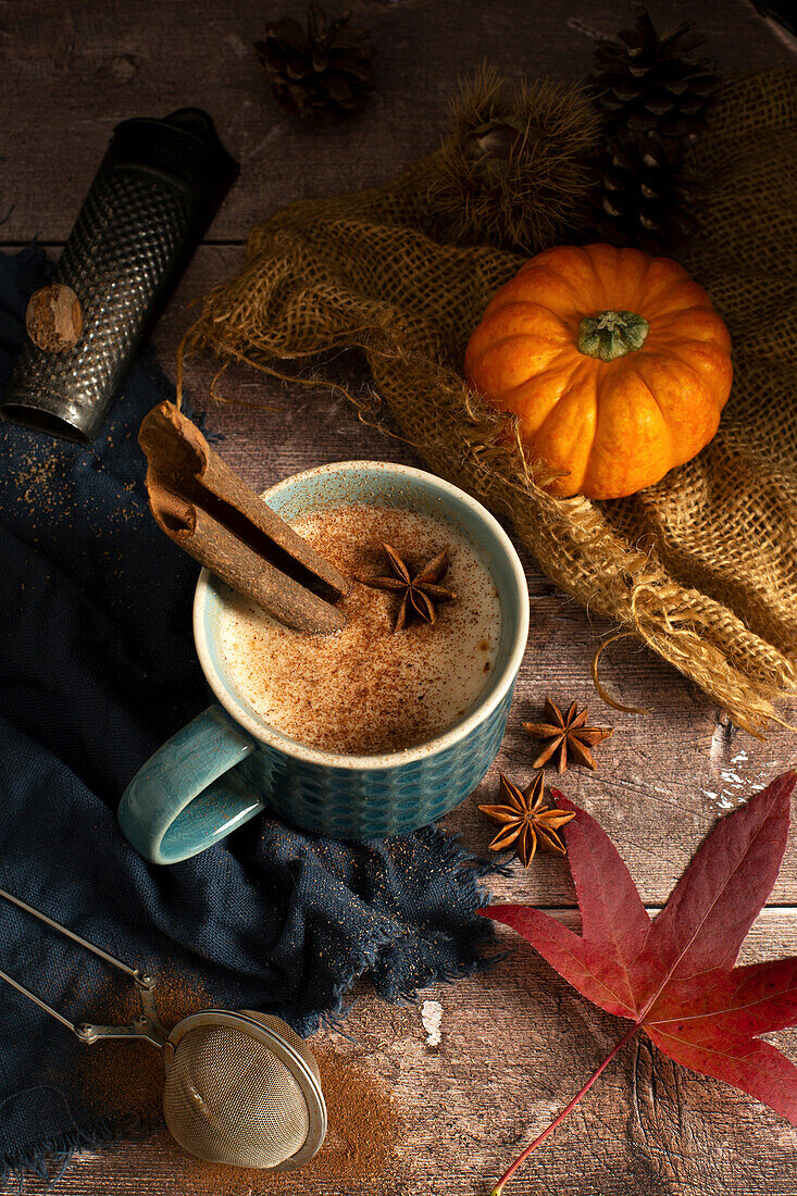 Pumpkin Spiced Latte im Becher mit Muskatnuss, Sternanis und Zimtstange