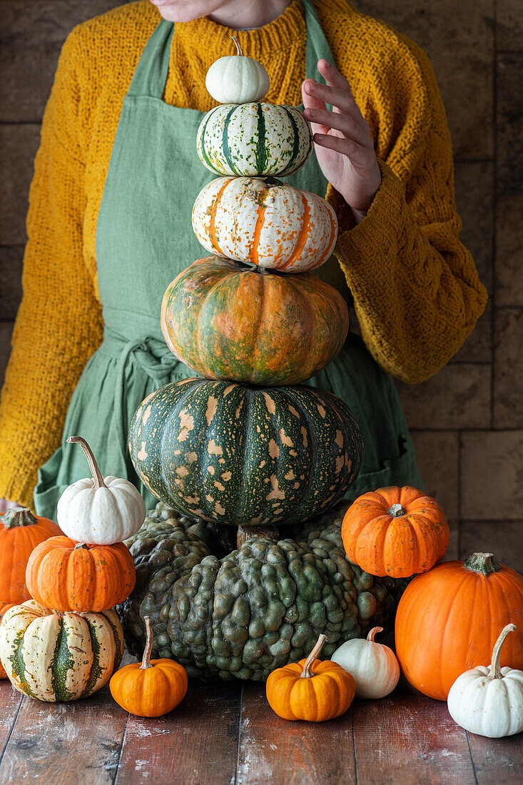 Woman behind stacked pumpkin varieties