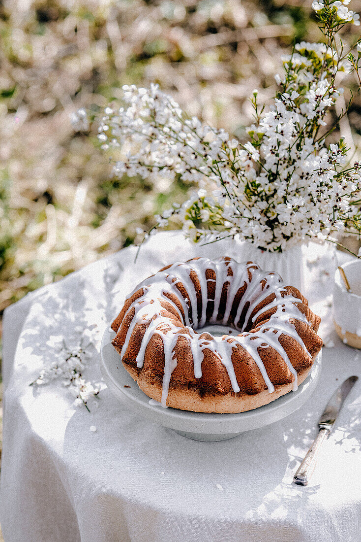 Frühlingskuchen mit Zuckerguss auf Gartentisch