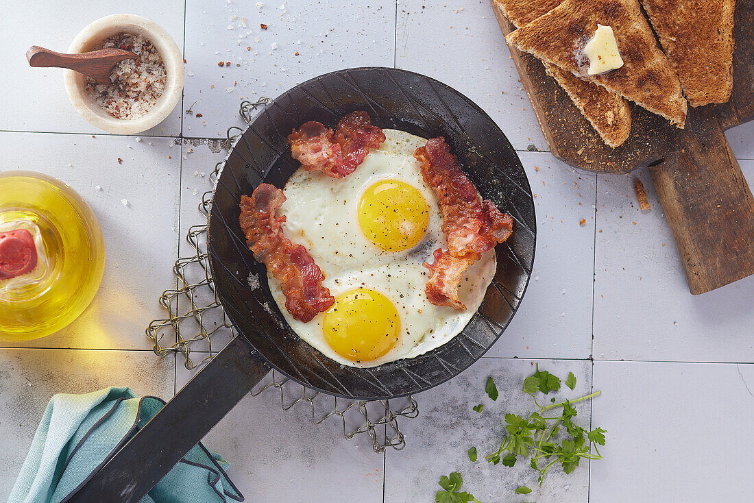 Fried eggs with bacon in a skillet, toast