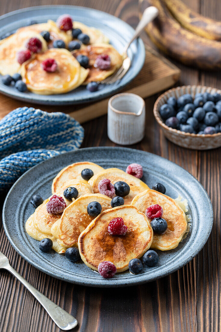 Yogurt banana pancakes with maple syrup, blueberries and raspberries