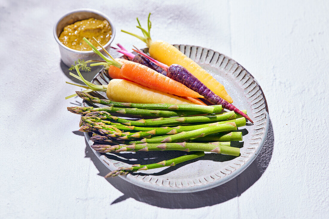 Bunte Mini-Karotten und grüner Spargel mit Pistou