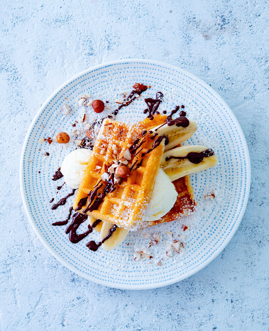 Belgische Waffeln mit Bananen, Eiscreme, Haselnüssen und Schokoladensauce